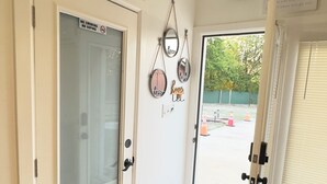 Un corridoio con una porta in vetro, un pavimento in legno e una porta con il cartello 'No Smoking'.