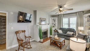 Una sala de estar con chimenea, un sofá, un sillón mecededor y un ventilador de techo.