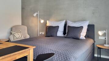 Une chambre moderne avec un lit, des lampes de chevet, une chaise et une petite table.