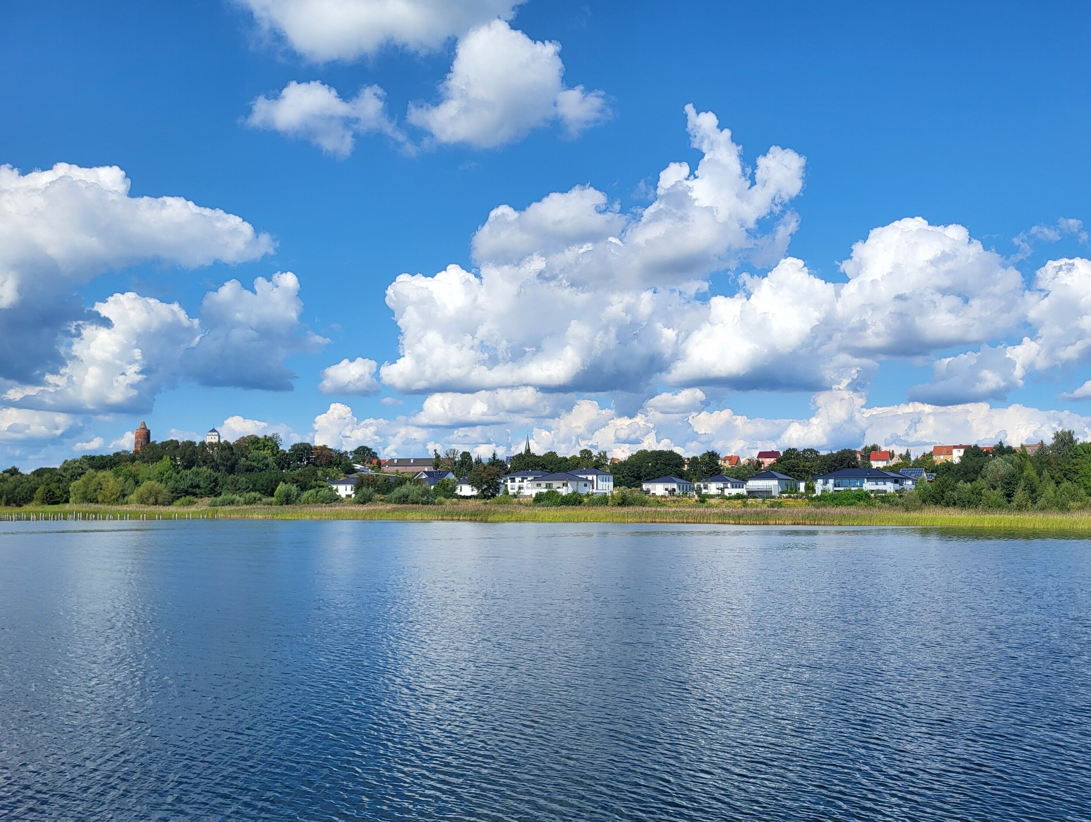 Un lago tranquillo con cielo sereno e nuvole sparse.