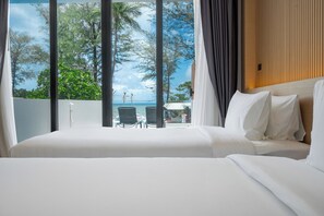 Une chambre d’hôtel avec un grand lit, une vue sur la plage et un balcon équipé de chaises.
