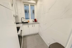 A compact kitchen with white cabinets, a window, and a sink.