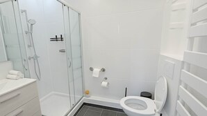A modern bathroom with a glass-enclosed shower, a toilet, and a vanity with drawers. - Elegant Paris 11 Apartment, Near Metro & Dining (Paris)
