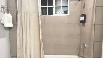 Une salle de bain avec une baignoire, une fenêtre et un porte-serviettes.
