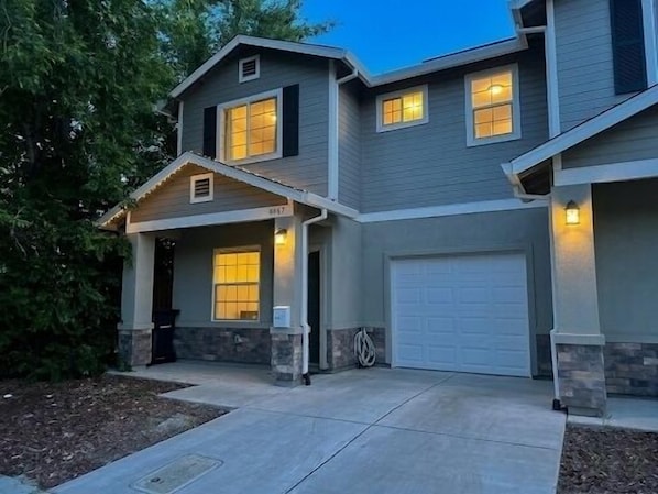 A two-story house with a garage, a covered front porch, and a landscaped front yard.