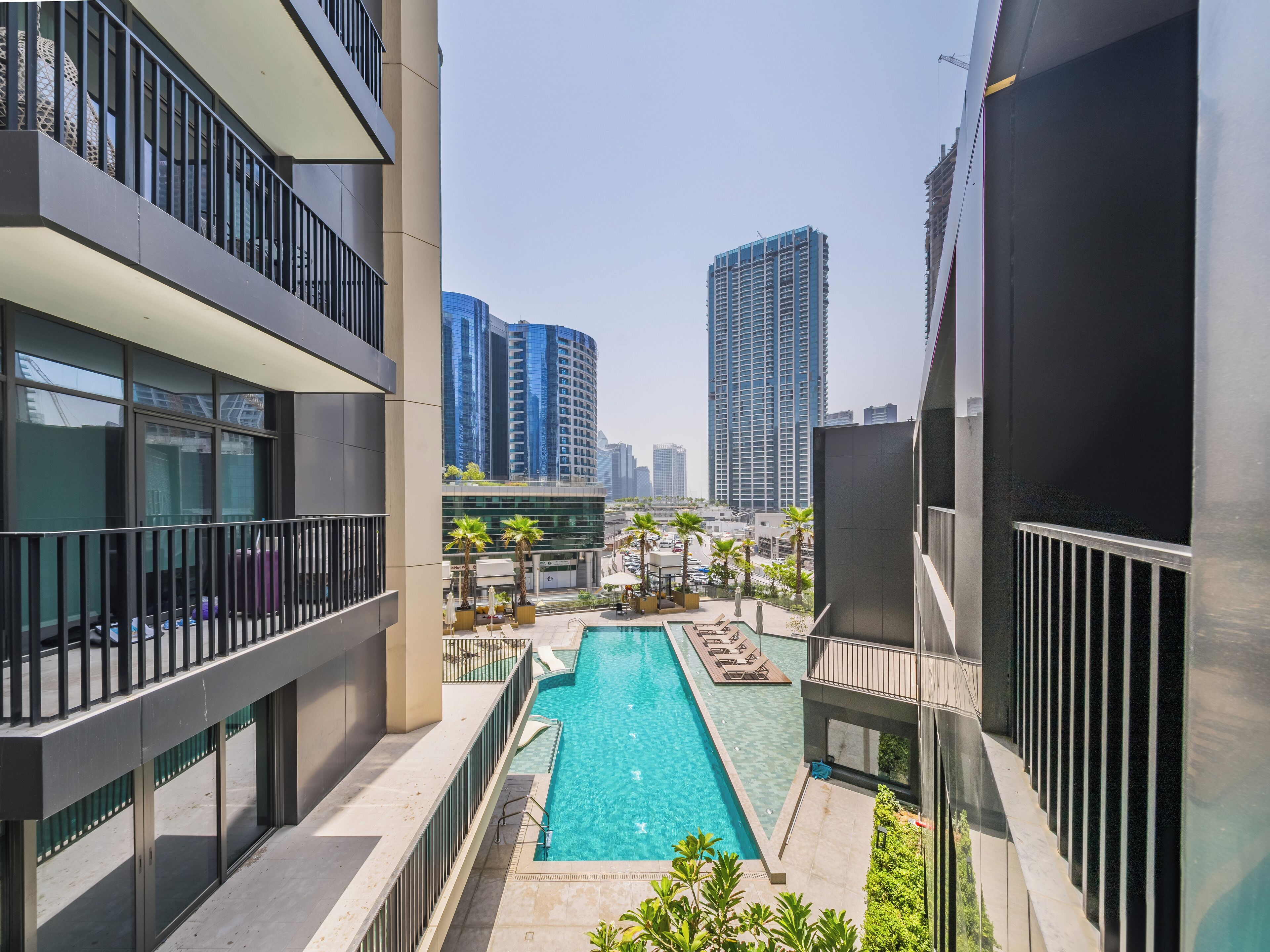 Ein modernes Gebäude mit Pool auf dem Dach, umgeben von hohen Wohnhäusern.