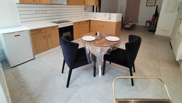 A compact kitchen with wooden cabinets, a white countertop, and a dining table with chairs. - "Le Nid Dauphinois" fully equipped - Ideal for business, couples & families! (L'Albenc)