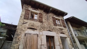 A stone building with wooden shutters, a balcony, and a small window. - "Le Nid Dauphinois" fully equipped - Ideal for business, couples & families! (L'Albenc)