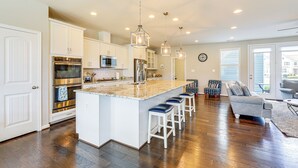 A spacious kitchen with white cabinetry, stainless steel appliances, and a central island with bar stools. - Spacious Townhome 2 Mi to Bethany Beach Boardwalk (Frankford)