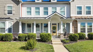 A two-story residential building with a front porch, a stone accent wall, and a small garden with trimmed bushes. - Spacious Townhome 2 Mi to Bethany Beach Boardwalk (Frankford)