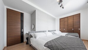 A modern bedroom with a large bed, wooden wardrobe, and a grey headboard. - GRANDIA 201 (Sapporo)