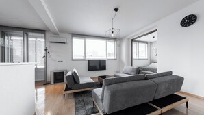 A modern living room with a grey sofa, a flat-screen TV, and a wooden floor. - GRANDIA 201 (Sapporo)