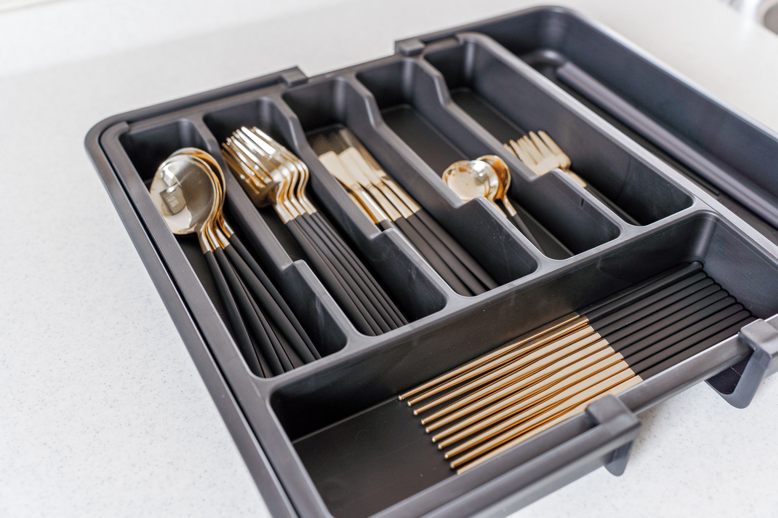 A black case with compartments containing various utensils like forks and spoons.