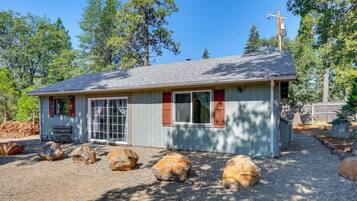 A small, single-story building with a sloped roof, large windows, and a gravel driveway.