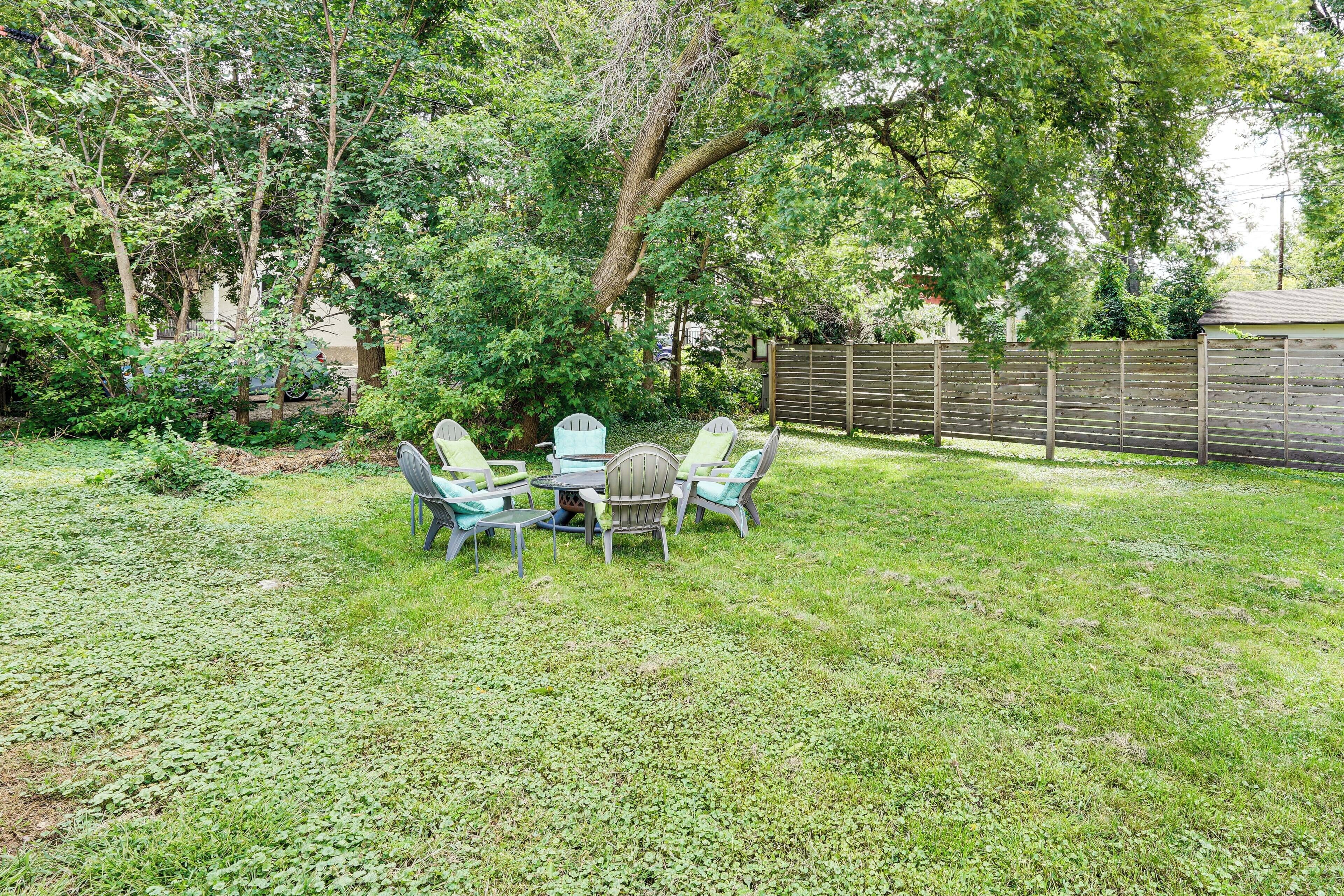 A backyard with a table and chairs, surrounded by trees and a wooden fence.