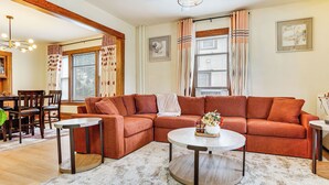 A living room with a sectional sofa, two coffee tables, and a dining area with a wooden table and chairs. - 1 Mi to University: Spacious Home in Minneapolis! (Minneapolis)