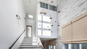 Un interior moderno con una escalera, una pared de madera con acabado envejecido y una lámpara colgante.