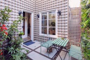 A courtyard with a green metal table and chairs, a wooden door, and a lattice wall.