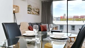 Un área de comedor moderna con una mesa de vidrio, sillas negras y un sofá al fondo.