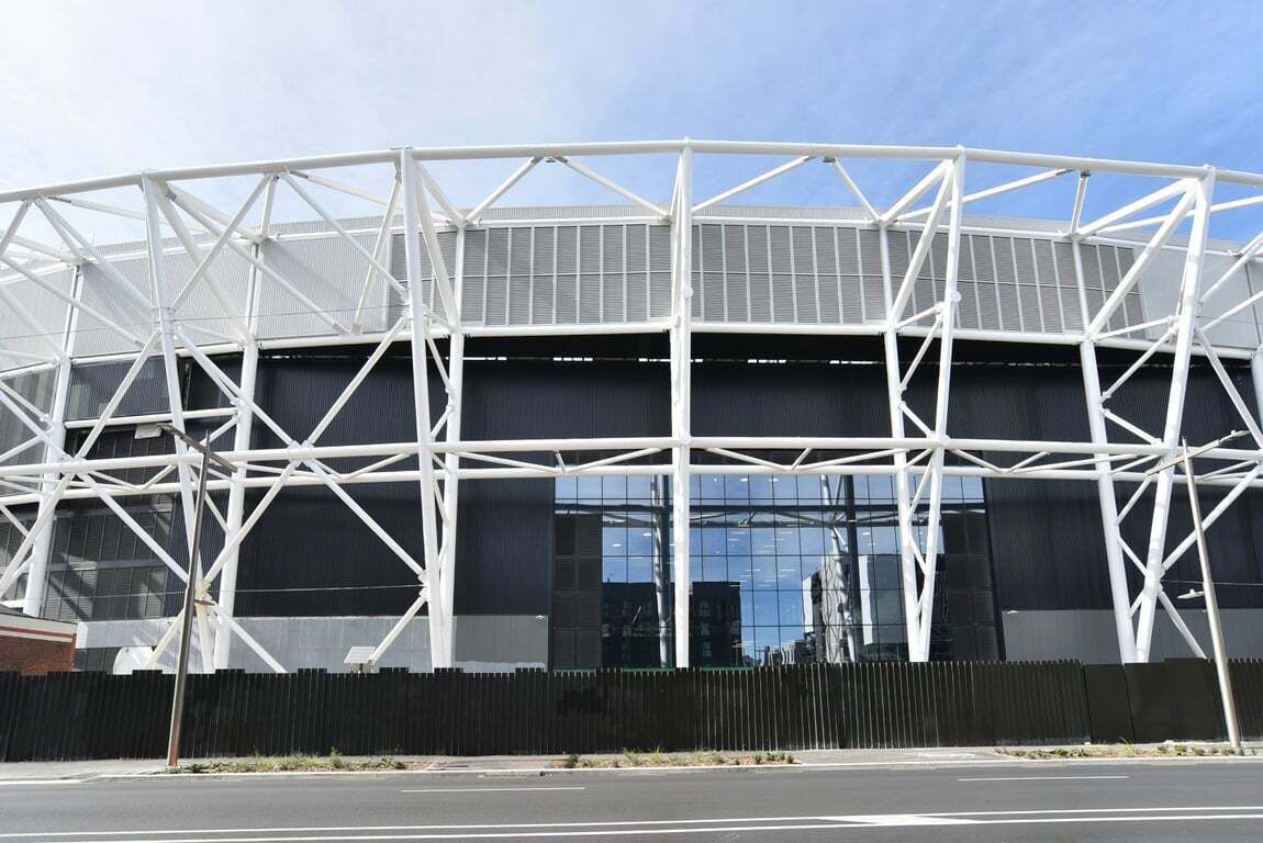 A modern stadium with a white metal framework and large glass windows.