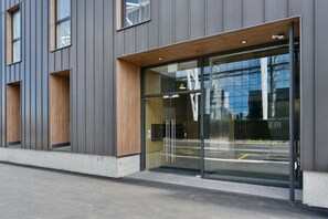 Un edificio moderno con amplios ventanales de vidrio y un alero de madera sobre la entrada.