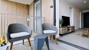Una sala moderna con dos sillones de mimbre, una mesita, un televisor y un mueble de madera.