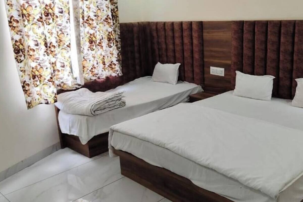 Ein Hotelzimmer mit zwei Einzelbetten und einem Doppelbett, alle mit weißer Bettwäsche.