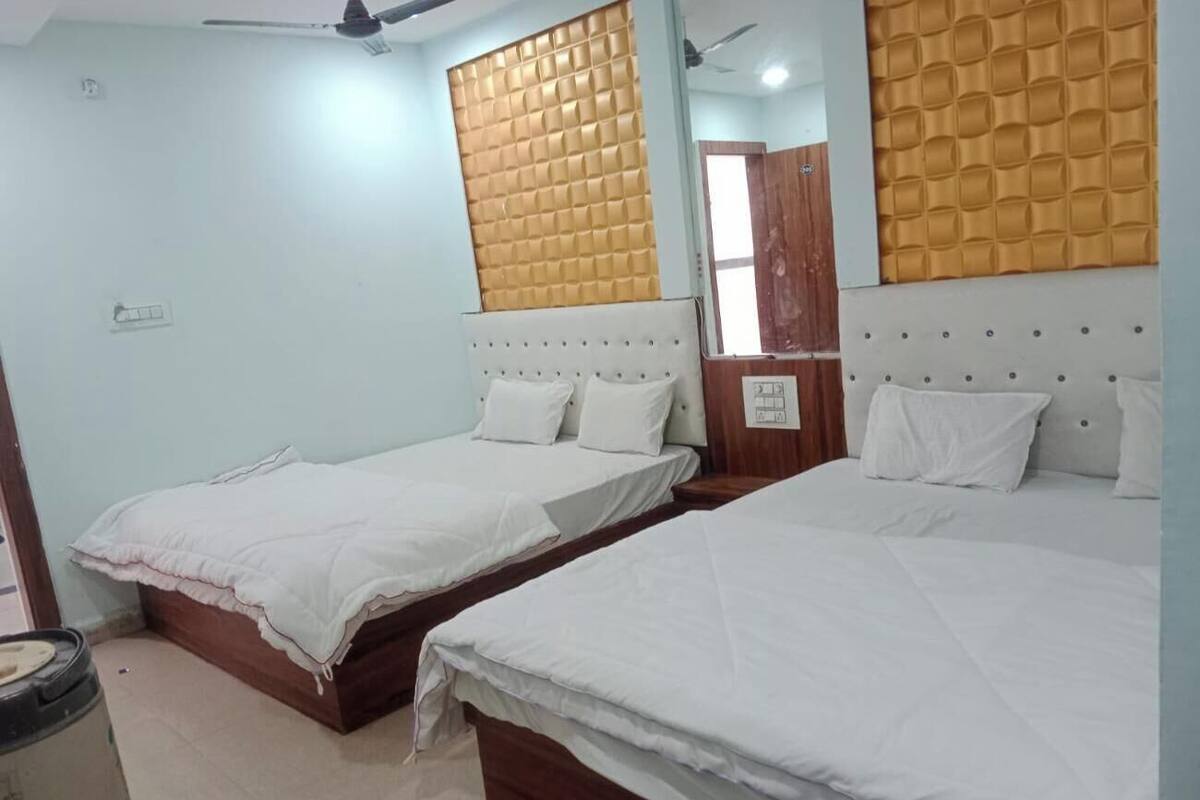 Ein Hotelzimmer mit zwei Einzelbetten, einem Holzkopfteil, einem Deckenventilator und einem an der Wand befestigten Spiegel.
