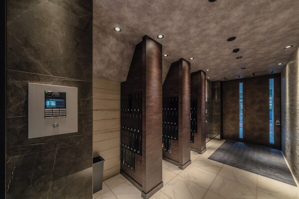 A modern elevator lobby with a digital display, marble walls, and a sleek design.