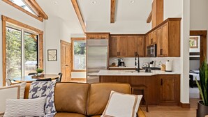 Une cuisine moderne avec des meubles en bois, un réfrigérateur en acier inoxydable et un grand îlot central.