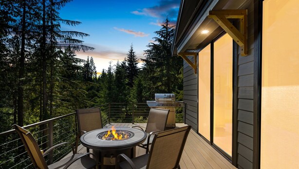 Une terrasse extérieure avec une table ronde et des chaises, un foyer et un barbecue.