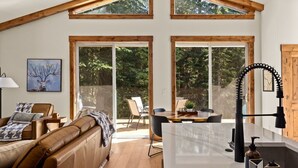 Un loft spacieux avec de hauts plafonds, des poutres apparentes, un grand espace de salle à manger et un coin salon confortable avec un canapé en cuir.