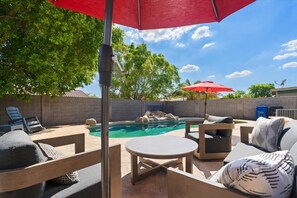 A backyard with a pool, patio furniture, and a red umbrella. - The Sun Club | Private Pool • BBQ • Outdoor Dining (Mesa)