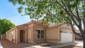 A single-story house with a beige facade, a tiled roof, and a garage. - The Sun Club | Private Pool • BBQ • Outdoor Dining (Mesa)