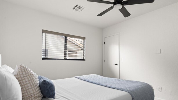 A bedroom with a bed, a window with blinds, a ceiling fan, and a door. - The Sun Club | Private Pool • BBQ • Outdoor Dining (Mesa)