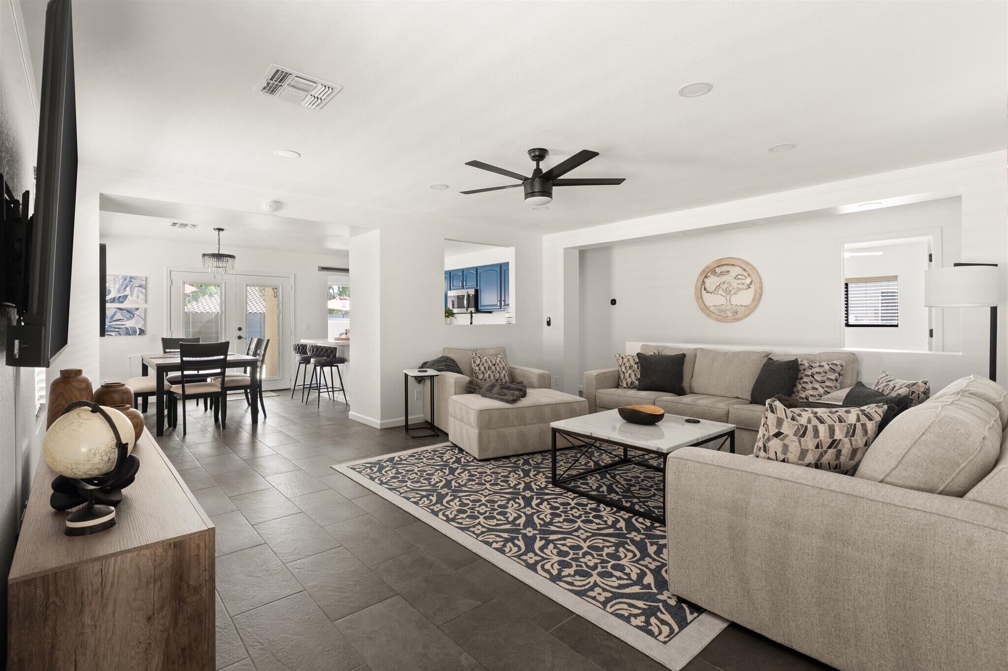 A modern living room with a sofa, coffee table, and a dining area with chairs and a table.