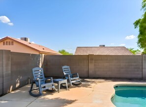 Un cortile con una piscina, due poltrone relax e un muro in mattoni.