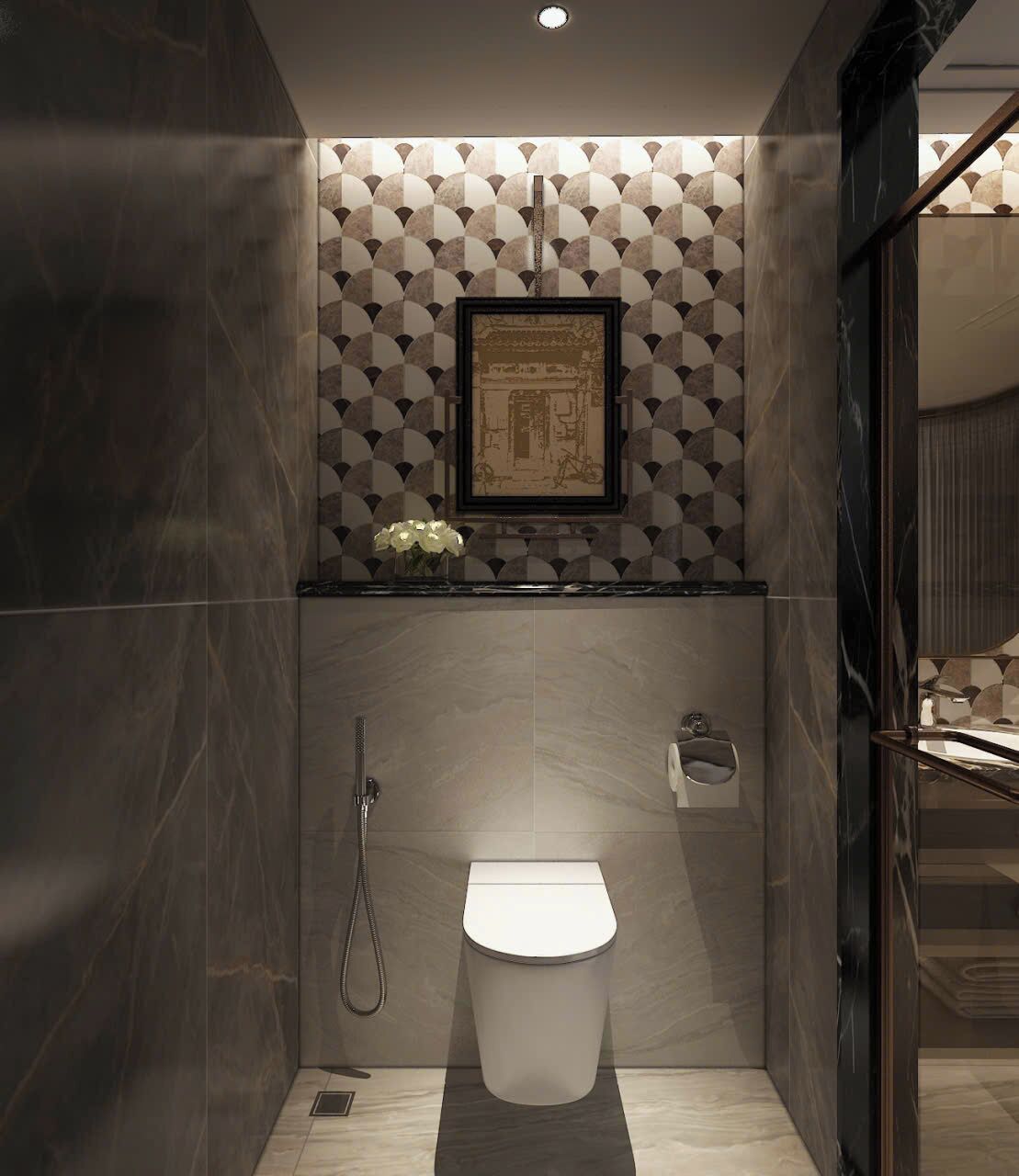 A modern bathroom with a geometric patterned wall, a framed picture, and a small flower arrangement.