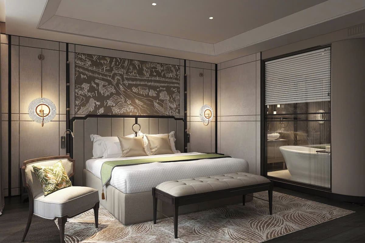 A modern bedroom with a large bed, a bench, a chair, and a wall-mounted artwork.
