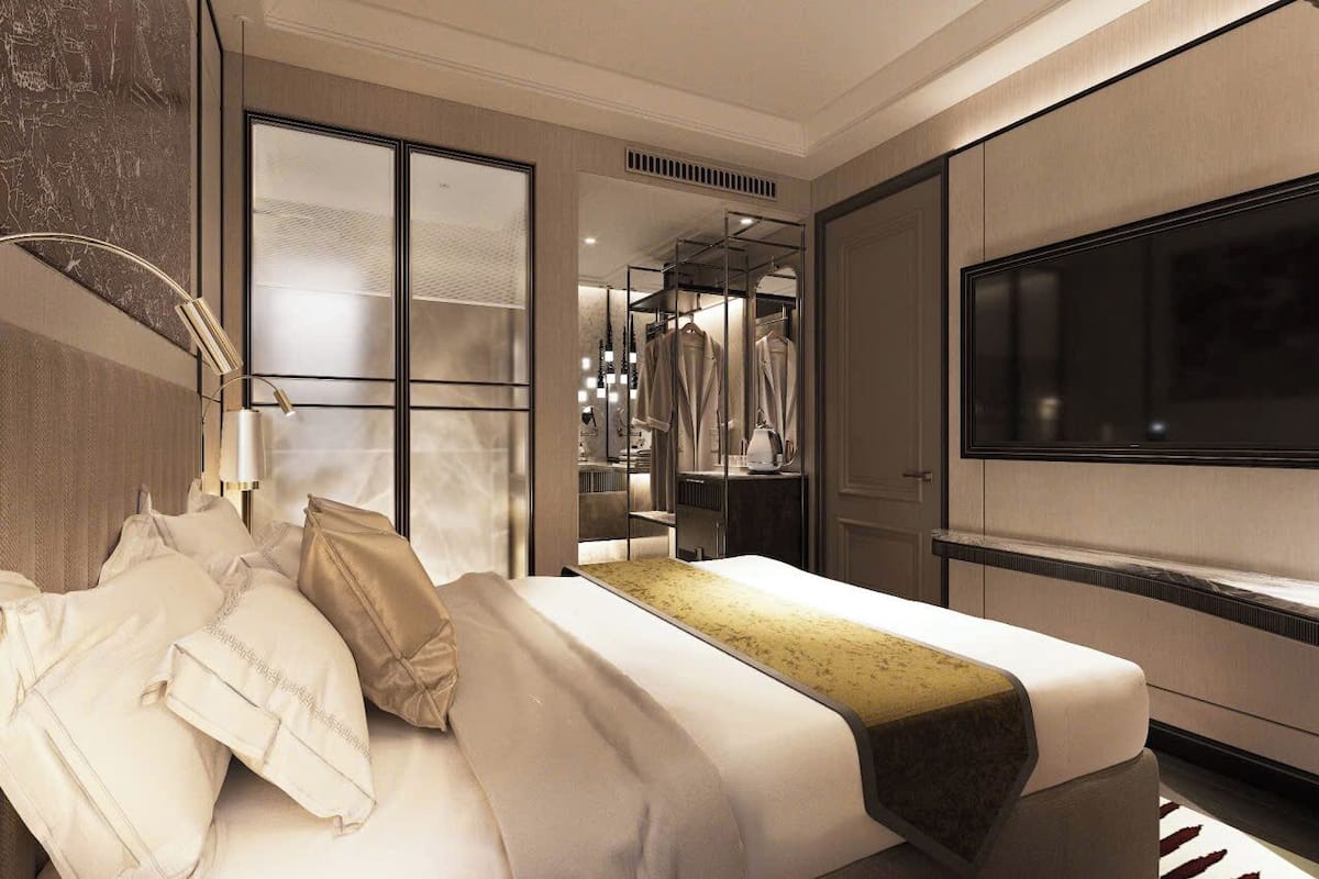 A modern hotel room with a large bed, a walk-in closet, and a TV on the wall.