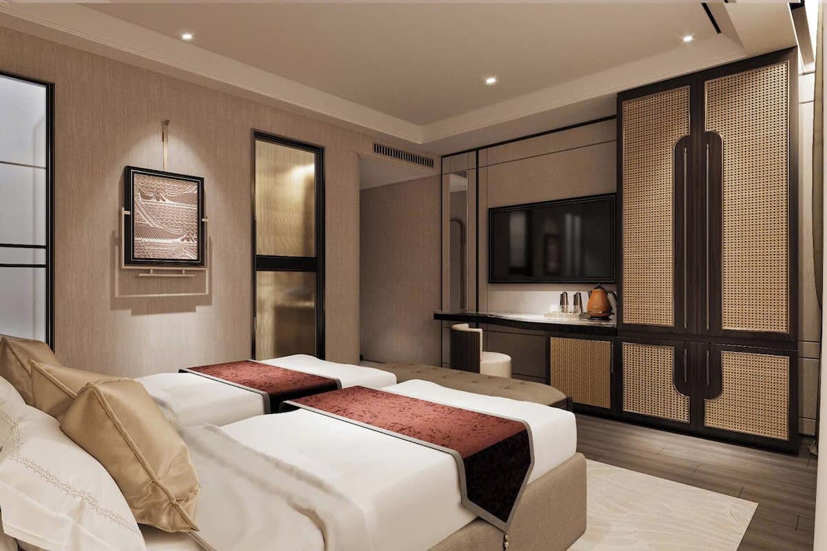 A modern hotel room with two beds, a flat-screen TV, a minibar, and a large window.