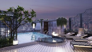 Uma área de piscina no terraço com hidromassagem, espreguiçadeiras e vista para a paisagem urbana.
