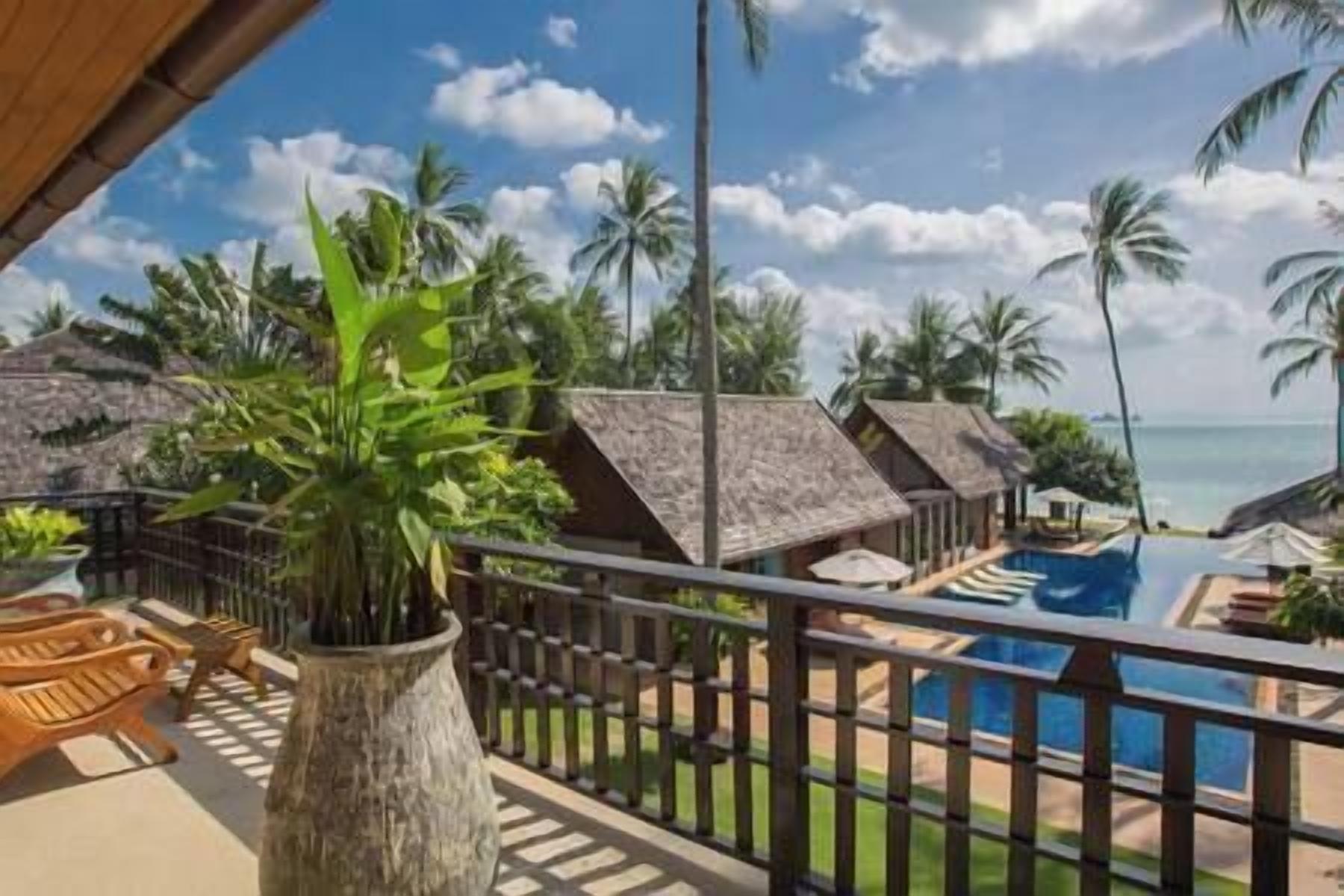 A resort with thatched-roof bungalows, a pool, and a view of the ocean.