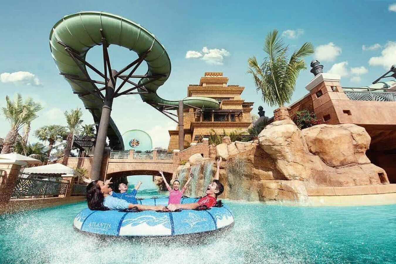 Een waterpark met een lange glijbaan, een zwembad en een gebouw in traditionele stijl.
