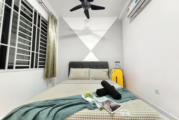 Un dormitorio con una cama, ventilador de techo, ventana con persianas y una maleta.