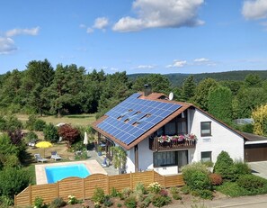 A house with a swimming pool, solar panels, and a garden.