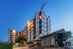 A multi-story hotel with a modern design, featuring balconies and a glass facade.