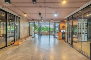A spacious hallway with glass doors leading to outdoor areas, a ceiling fan, and a reception desk.