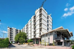 A multi-story hotel with a modern design, featuring balconies and a covered entrance.
