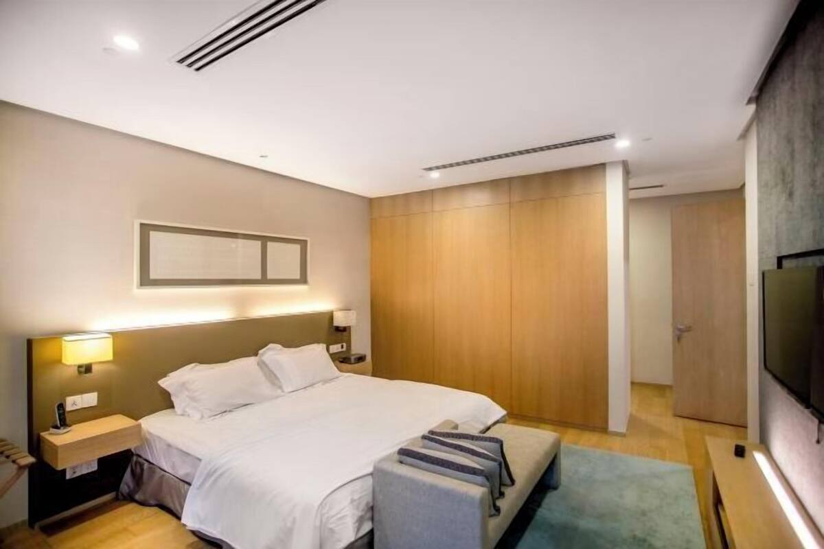 Een moderne hotelkamer met een groot bed, nachtkastjes, een flatscreen-tv en een houten garderobe.